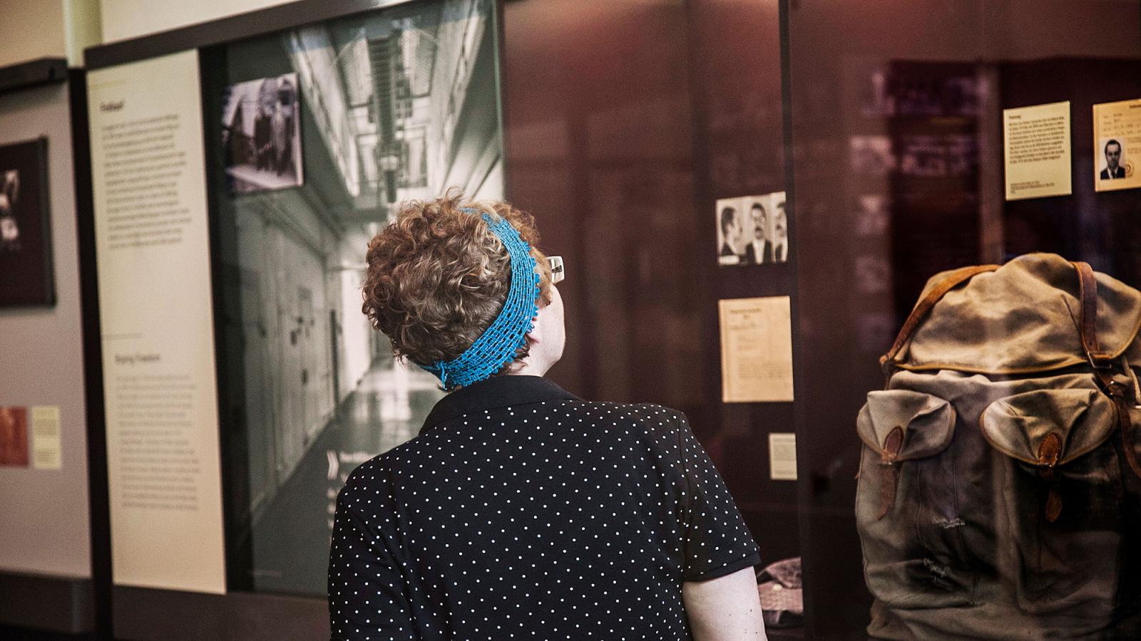 Besucherin vor einer Austellungsvitrine mit historischem Rucksack