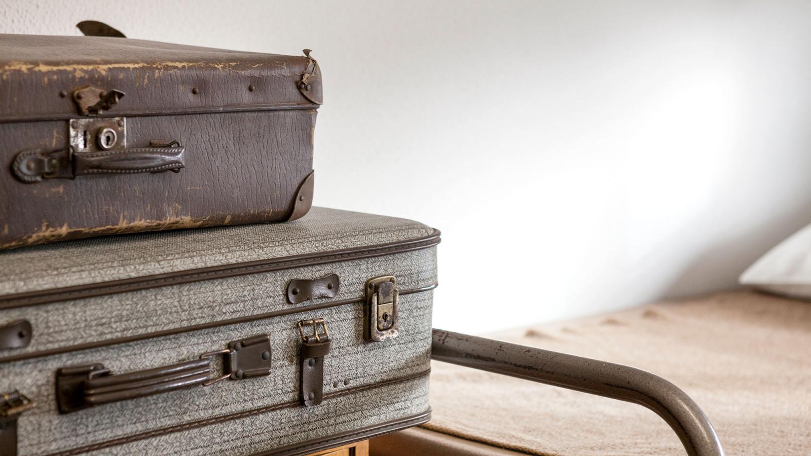 Detailansciht zweier Koffer in der Ausstellung. Im Hintergrund ein Doppelstockbett.