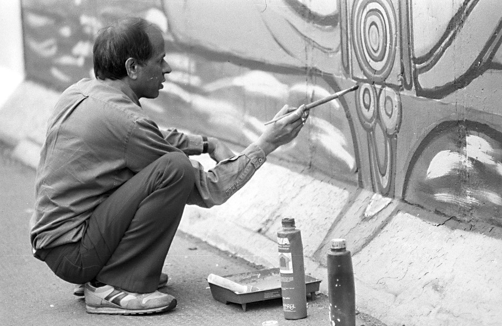 Künstler malt Bild an der East Side Gallery
